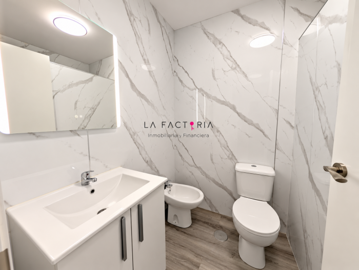 Baño moderno con mármol y logo inmobiliario.png